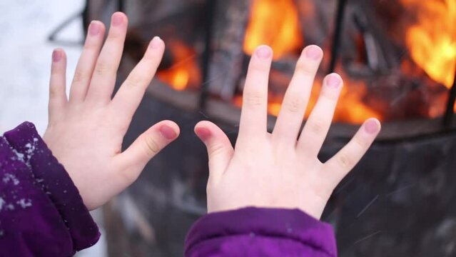 Close up of hands of girl warming themselves by fire outdoor