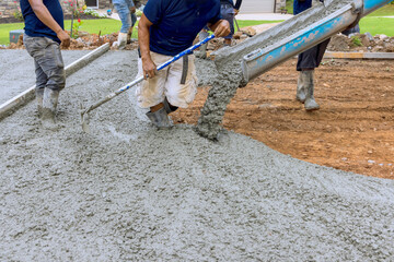 Using concrete mixing truck workers poured wet cement onto driveway of new house