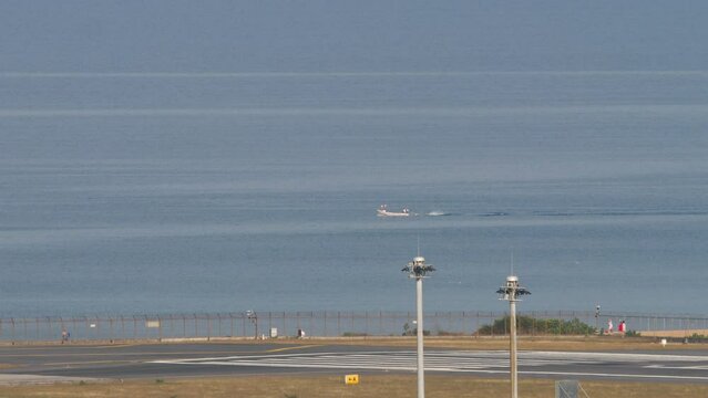 Ronway 09 of Phuket airport, and longtail fisher boat in ocean near airport.