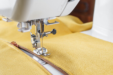 Modern sewing machine with yellow velours fabric. Sewing process clothes, curtains upholstery....
