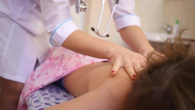 Female hands make light warming massage on back of lying boy.