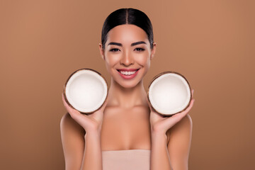 Portrait of gorgeous lady holding two coconuts enjoying vitamins procedure for skin isolated on...