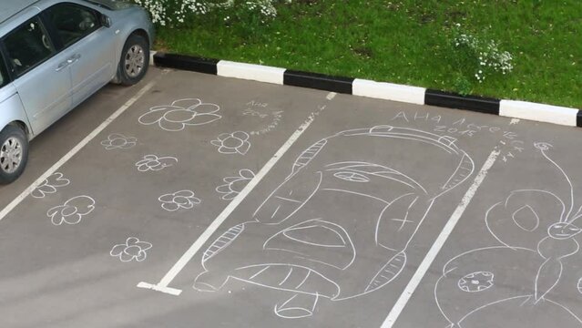 Different chalk drawings on car parking. Text: Anya Losevskaya