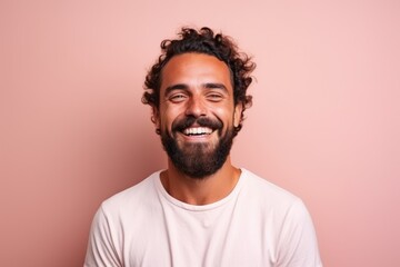 Portrait of a handsome young man with curly hair smiling against pink background - obrazy, fototapety, plakaty