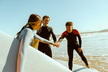 Group of surfers greet each other by shaking hands before surfing on waves in ocean
