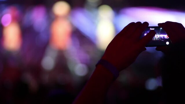 Hand is holding cellphone and shooting the concert in Red club.