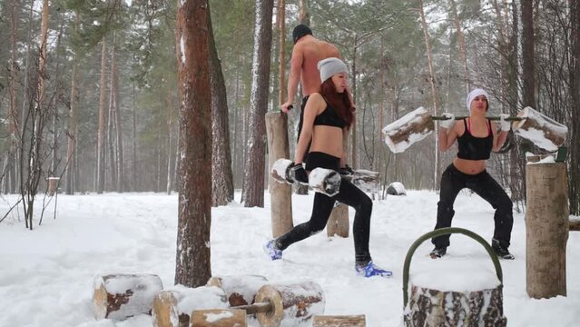 Two girls do exercises with wooden dumbbells and guy parallel bars dips