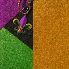 Mardi Gras beads with Fleur de lis, in glittering green, purple, and gold. Sparkling festive background for Mardi Gra in traditional colors.