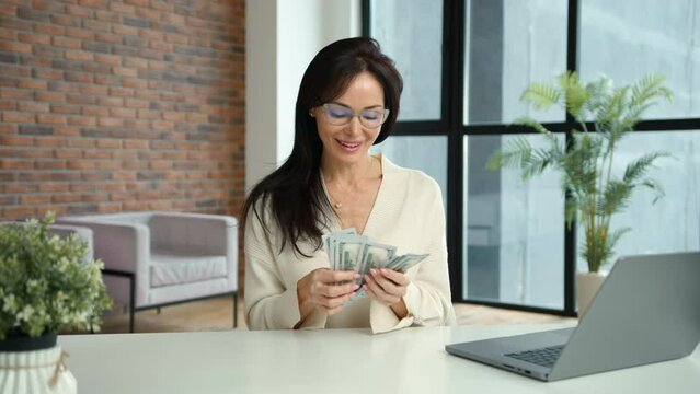 A businesswoman counts her earnings with a smile, holding the money close and feeling a sense of accomplishment and financial success. Camera 8K RAW. 