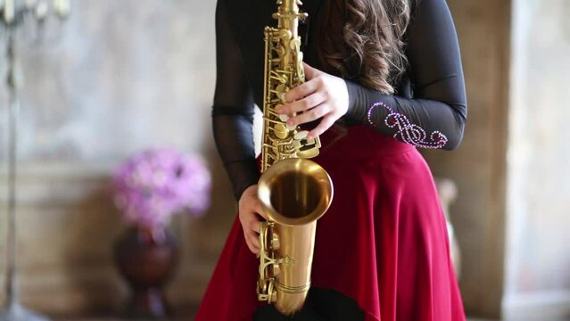 Close up of hands of girl playing saxophone in room