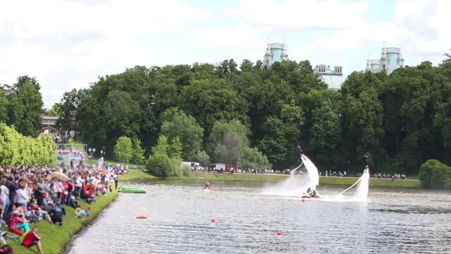 Sportsmans ATV and flyboard act in park on lake in front of audience