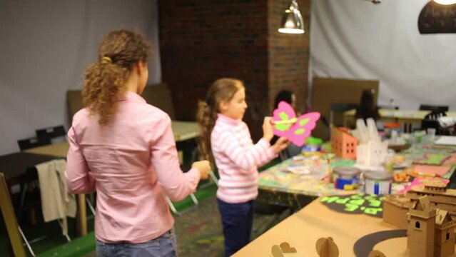 Happy woman and girl paint cardboard crafts on table