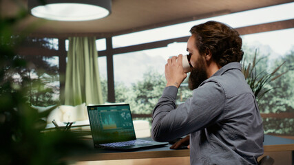 Rich investor hopping online on laptop to help his employees from his expensive opulent villa in...