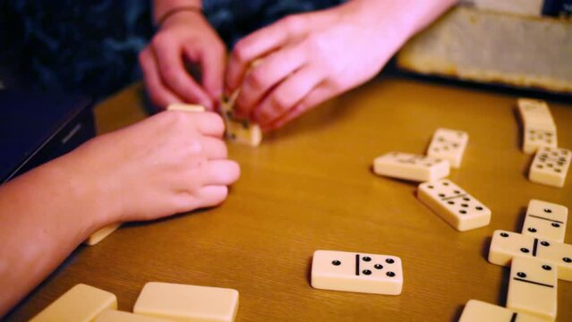 Female hands play with white domino at table indoor
