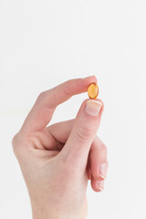 Woman holding and taking yellow vitamin pill in hand