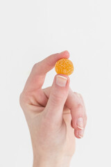 Woman holding orange gummy vitamin in hand