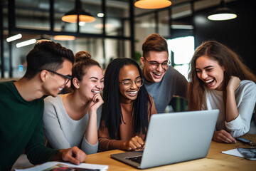 Gruppe lächelnder junger Menschen, die in einem Büro auf einen Laptop schauen, Kollegen mit Spaß und Erfolg im Büro