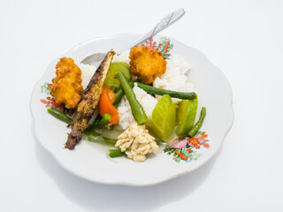 Rice with fried fish and vegetables in white plate on white background