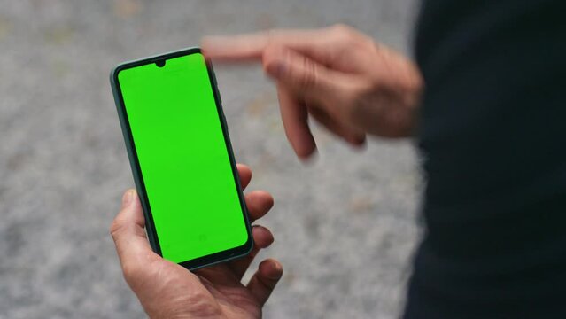 Closeup finger touching green smartphone screen. Hand holding mockup cell device