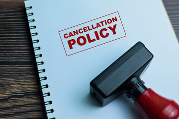 Red Handle Rubber Stamper and Cancellation Policy text above book isolated on wooden background