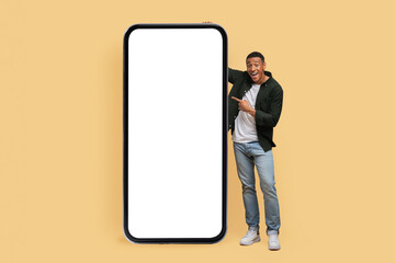 Excited young black man posing by phone with white screen