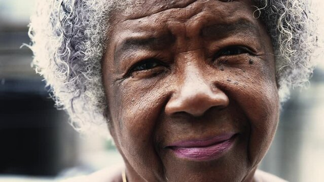 African American elderly lady in 80s with solemn expression expressing old age and wisdom. Gray hair wrinkled portrait of a black senior woman staring at camera outside in drizzle