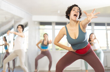 Fototapeta premium Sporty young woman dancing modern dance at class with his friends
