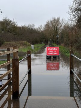 Red road closed due to flooding sign on the park path flooded with water