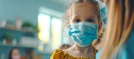 Protecting loved ones during a pandemic by teaching basic hygiene rules and preventive measures against Covid-19, viruses, and flu. The girl wearing a protective mask plays with her sister at the
