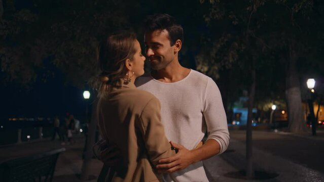 Married people embracing street in lamppost light. Affectionate girl bonding man