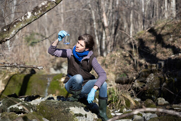 Female Biologist Researcher Collecting Data on Water Pollution on Field in a Forest