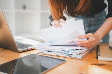 Businesswoman working in Stacks of paper files for searching and checking unfinished document achieves on folders papers at busy work desk office.