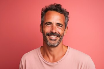 Portrait of a happy mature man smiling and looking at the camera against pink background