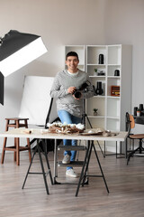 Young male photographer with professional camera working in studio