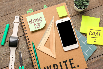 Sticky notes with stationery, mobile phone and smartwatch on wooden background