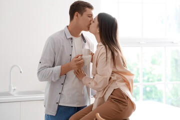 Happy young couple kissing in kitchen