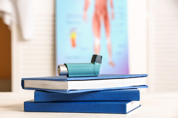 Asthma inhaler with books on table in doctor office - obrazy, fototapety, plakaty