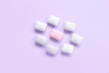 Tasty chewing gums on lilac background