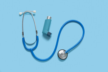Stethoscope with asthma inhaler on blue background