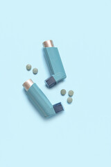 Asthma inhalers with pills on blue background