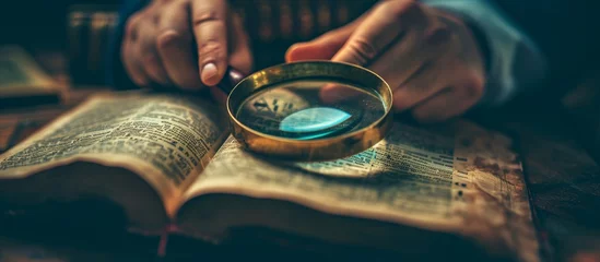 Fotobehang Someone studying Christianity using the Bible, research, and a magnifying glass to understand the concepts of religion, the Holy Spirit, and God's gospel for worship, learning about spiritual © TheWaterMeloonProjec
