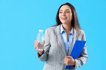 Young businesswoman with clipboard and bottle of water on color background