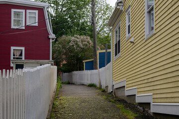 A narrow walkway or pathway behind bright, and colorful houses painted red, blue, and yellow. The...