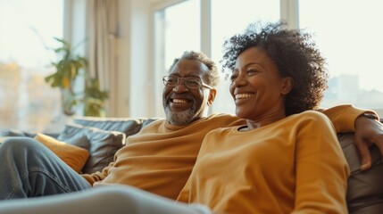 Various couples watch TV Pointing and laughing in a sunny living room.