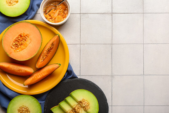 Plate and board with tasty ripe melons on white tile background