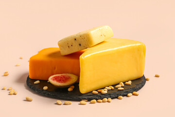 Board with tasty cheese, nuts and fig on beige background