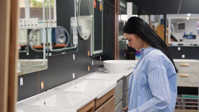 Woman chooses furniture for bathroom in shop, hardware store shopping