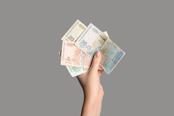 Female hand holding Bulgarian lev banknotes on grey background