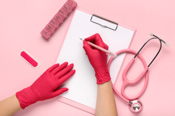 Doctor writing in clipboard on pink background, top view
