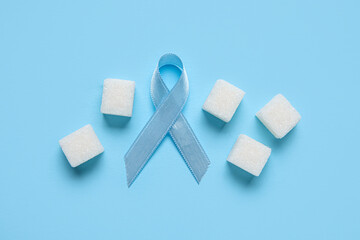 Awareness ribbon with sugar cubes on blue background. Diabetes concept